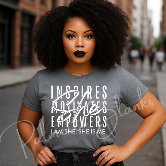 woman wearing a gray t-shirt with empowering text: “Inspires, Motivates, Empowers, She. I Am She. She Is Me.” Styled for a confident, modern look in an urban setting.